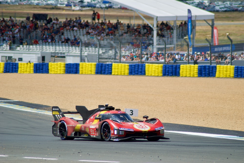 a red race car driving down a race track