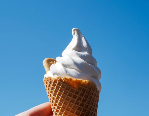 A swirl of Hokkaido milk soft serve ice cream against a bright blue sky