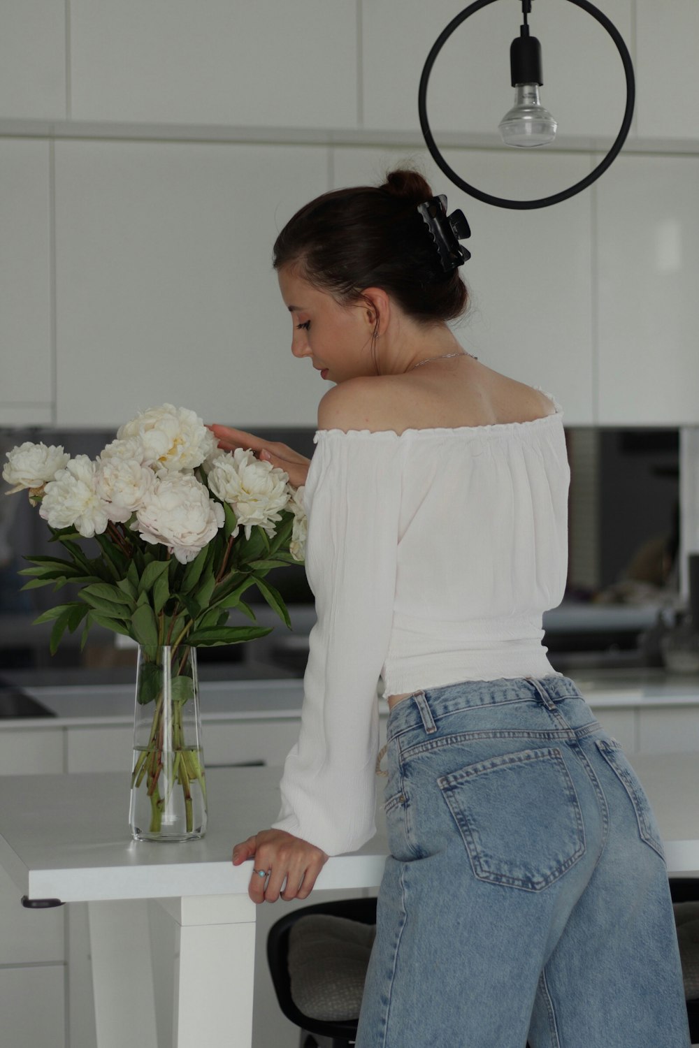 a woman standing at a table with a vase of flowers