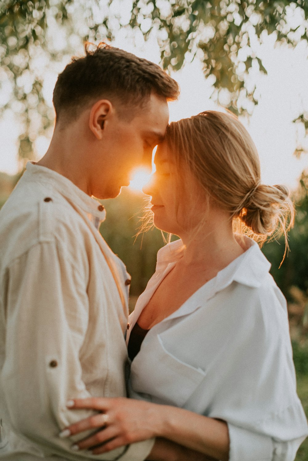 a man and a woman standing next to each other under a tree