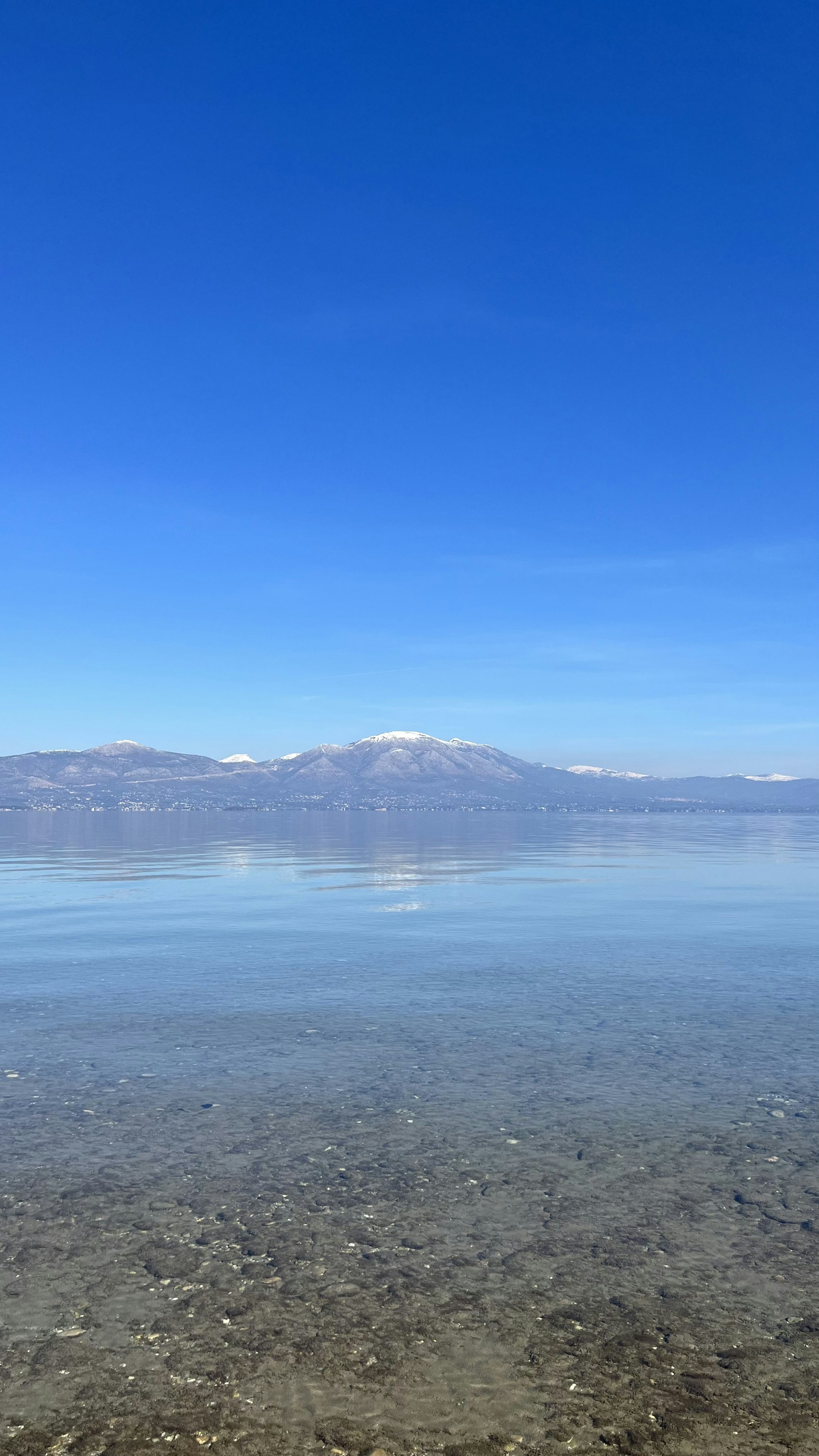 A serene lakeside scene with crystal-clear water and snow-capped mountains in the background, perfect for a tailored tour moment.