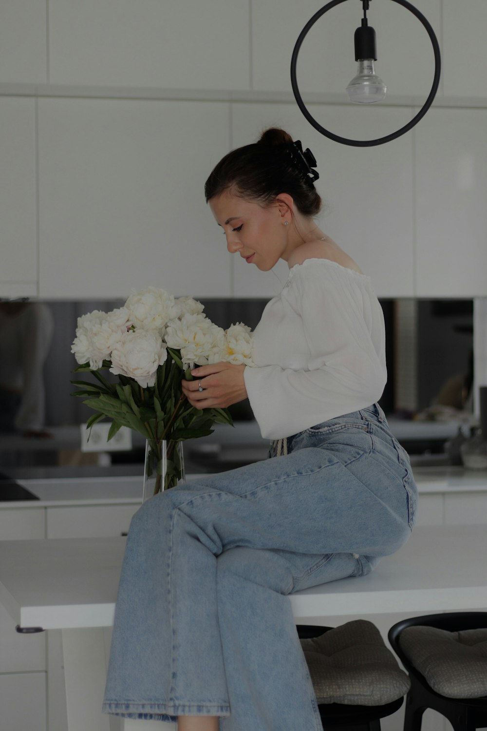 a woman sitting on a counter with a bouquet of flowers