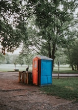 a blue and red portable toilet in a park