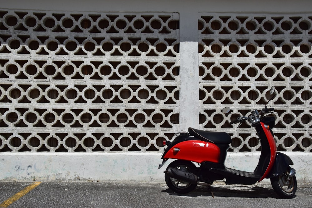 a red scooter parked in front of a white fence