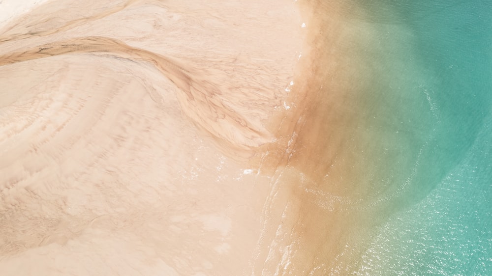 an aerial view of a sandy beach with blue water