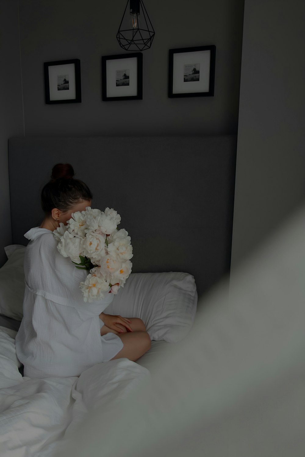 a woman sitting on a bed holding a bouquet of flowers