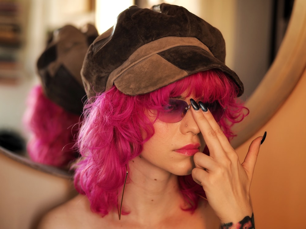 a woman with pink hair wearing a hat and sunglasses