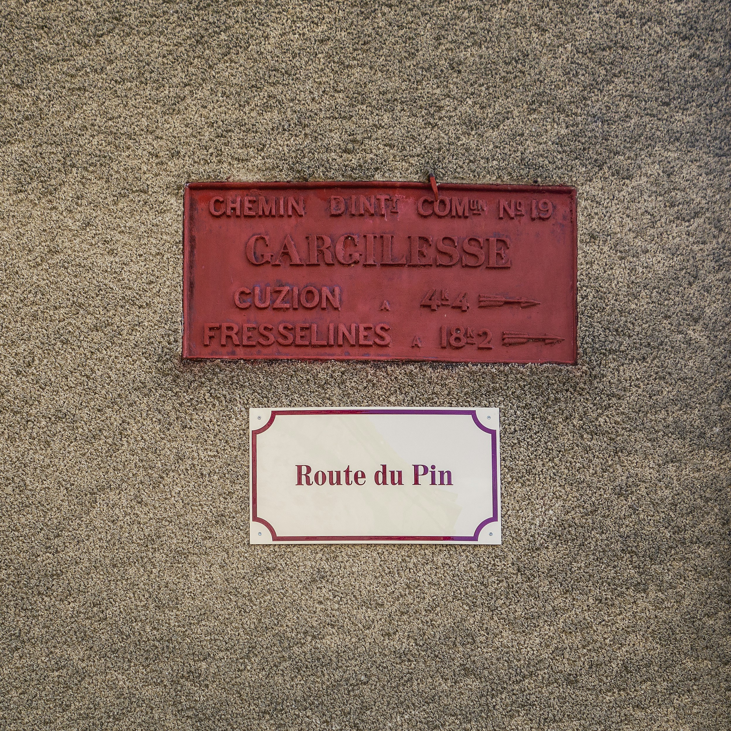 a red sign sitting on the side of a wall next to a white sign