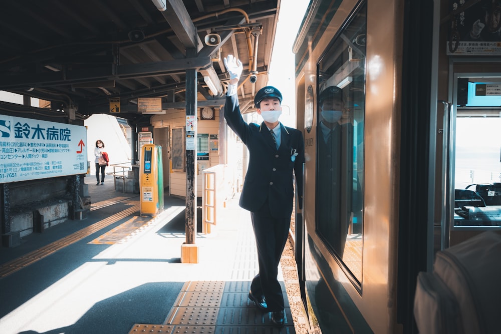 Un hombre con traje y sombrero parado en una plataforma de tren