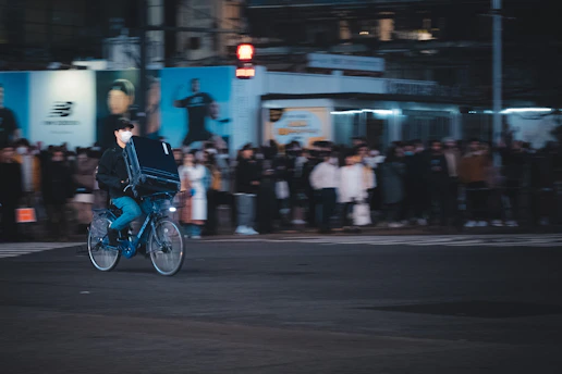 A delivery courier riding a bicycle through a city street, carrying a package.