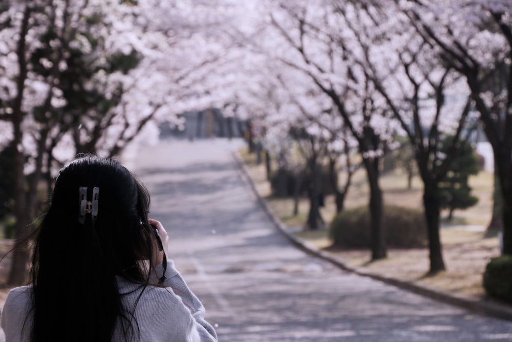 a woman walking down a tree lined street