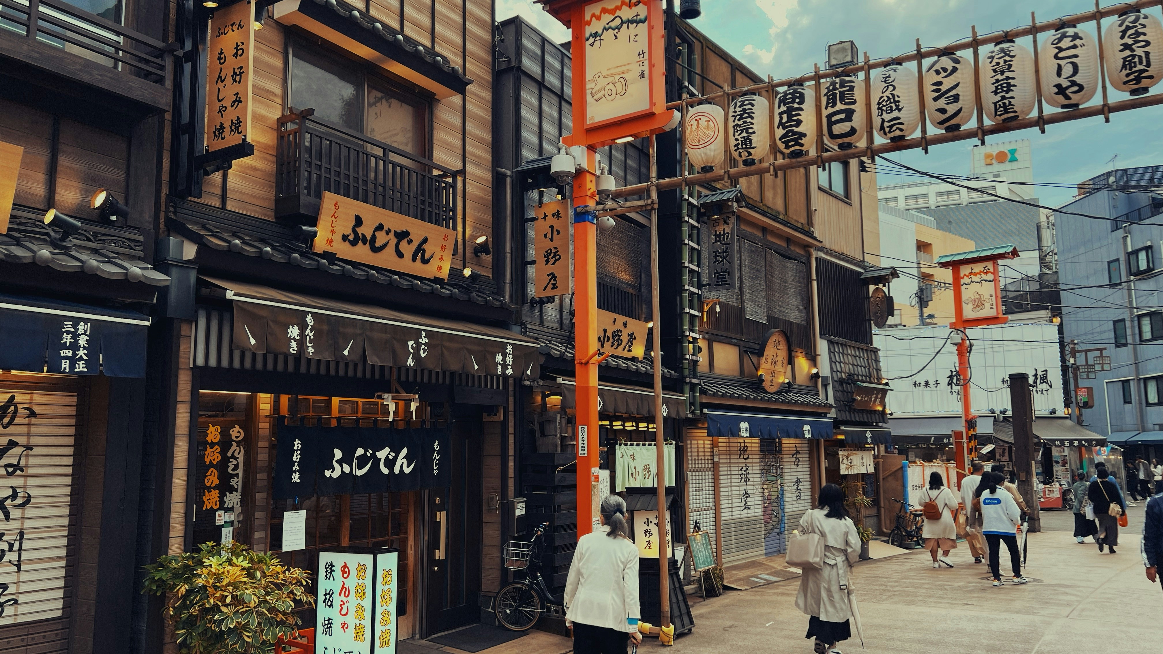 Nakamise shopping street in Asakusa Tokyo lined with traditional red lanterns and souvenir shops leading toward Senso-ji temple at dusk