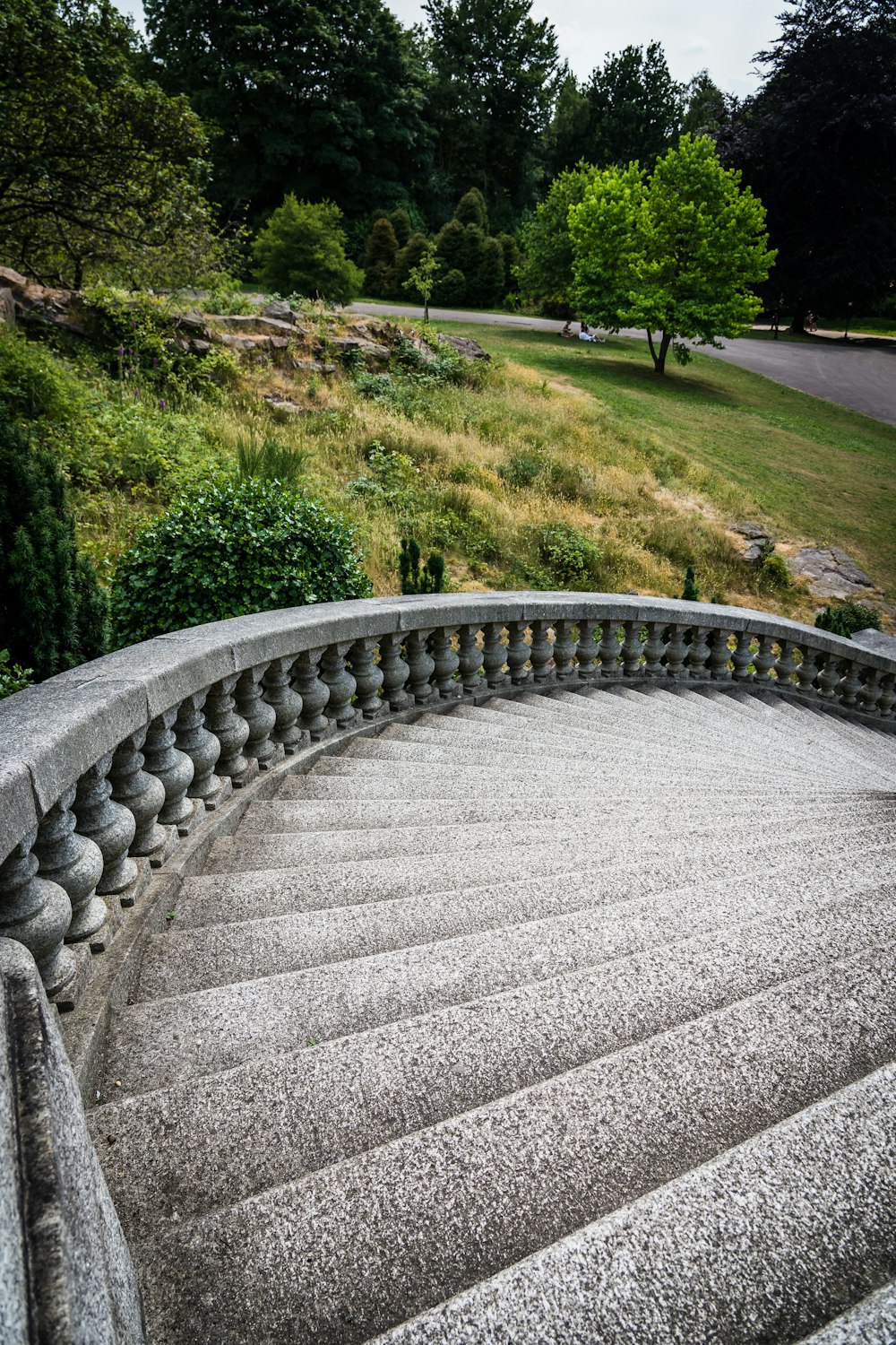 a spiral staircase in a park with trees in the background