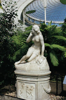 a statue of a woman sitting on top of a rock
