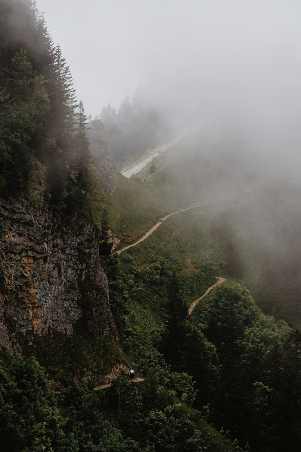 a foggy mountain with a winding road on the side