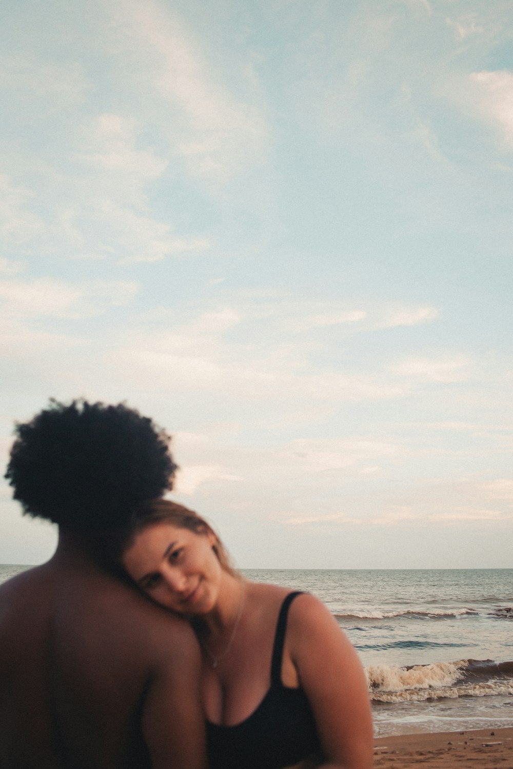 a woman in a bikini standing next to a man on the beach