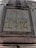 A weathered concrete sign on a building facade with engraved and spray-painted text. The engraved text includes 'CARRETERA GARCIA MORENO', while the spray-painted text in red and yellow partly covers the sign. The structure features classical architectural elements.