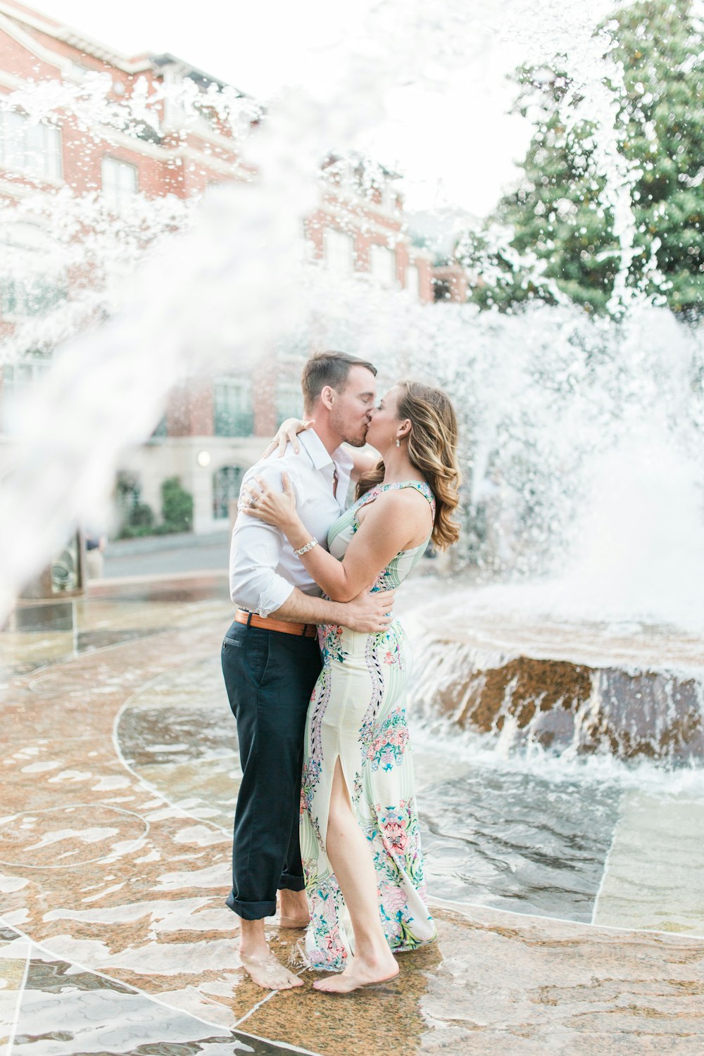 a man and woman kissing in front of a fountain