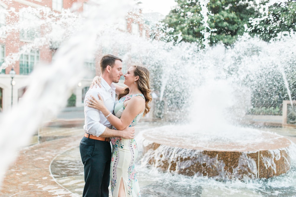 a man and a woman standing in front of a fountain