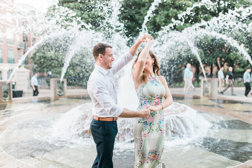 a man and woman dancing in front of a fountain