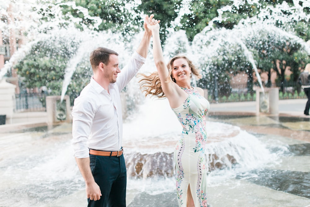 um homem e uma mulher dançando em frente a uma fonte