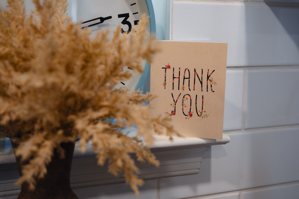 a thank you note sitting next to a clock