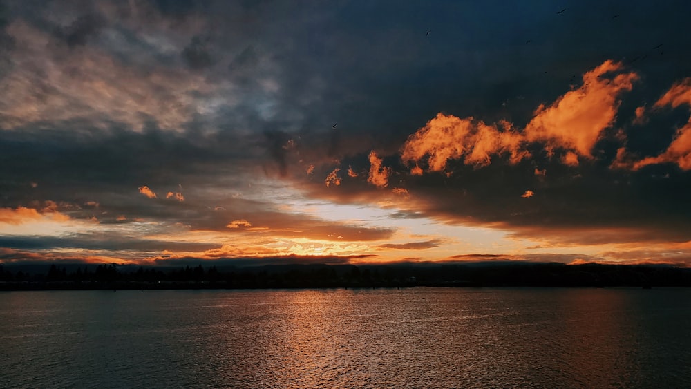 a sunset over a body of water with clouds in the sky