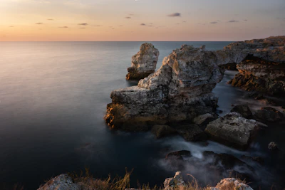 A panoramic shot of a rugged coastline under a soft pastel sky.