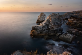 A pastel-hued Mediterranean coastal scene with soft sunlight over calm waters, evoking the serene vibe of le coquers.