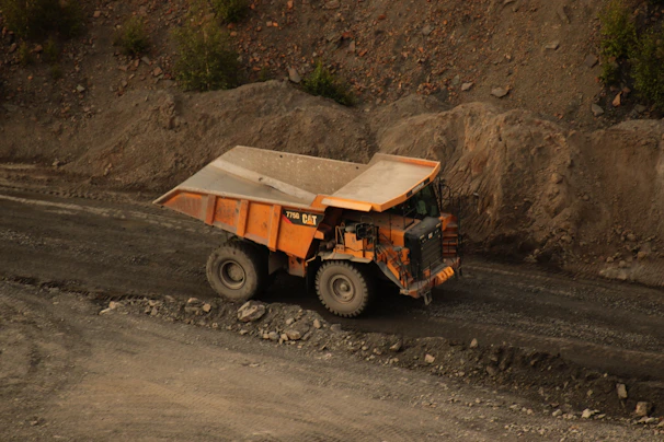 Robust black and yellow dump truck loaded with rocks driving on a dirt road
