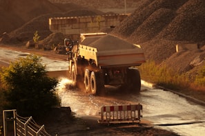 Workers guiding a dump truck unloading gravel at a highway expansion project