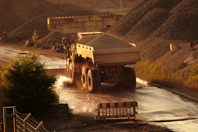 A rugged dump truck loaded with gravel driving along a forested road in the Fraser Valley.