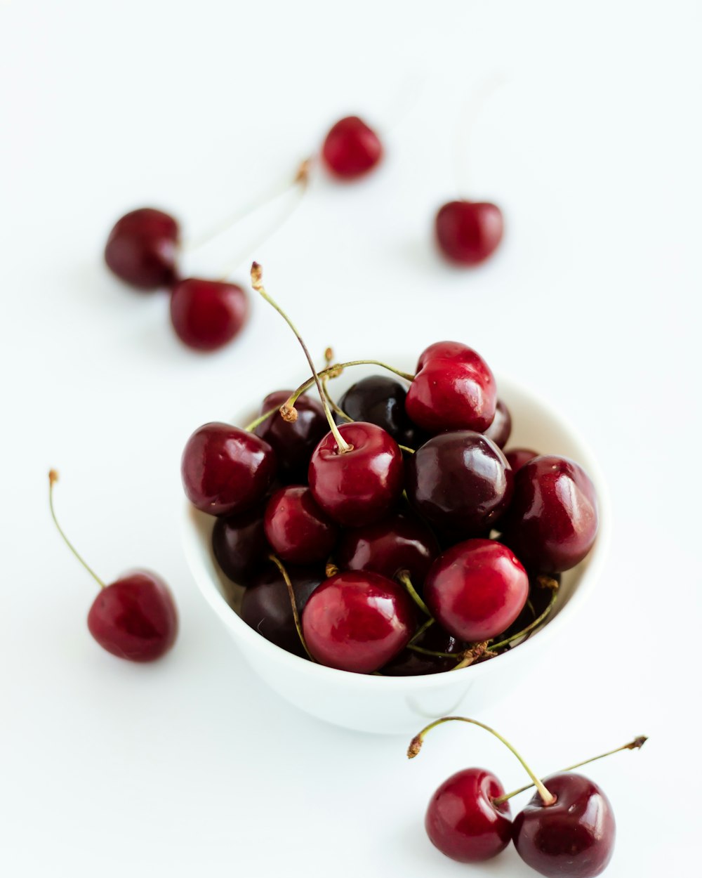 a white bowl filled with cherries on top of a table