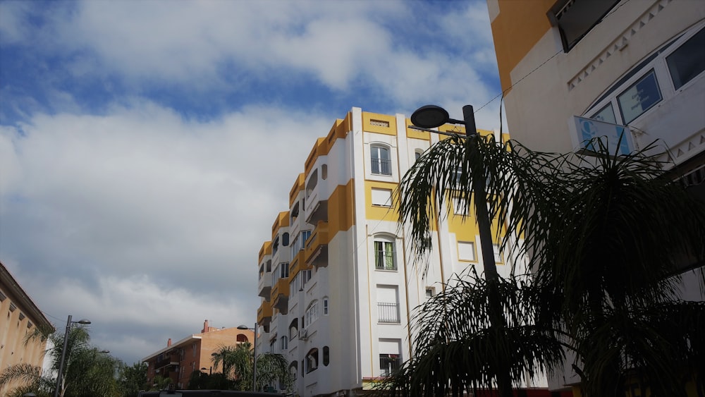a tall white and yellow building next to a palm tree