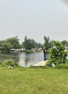 A beginner angler casting a line into a calm suburban lake surrounded by trees.