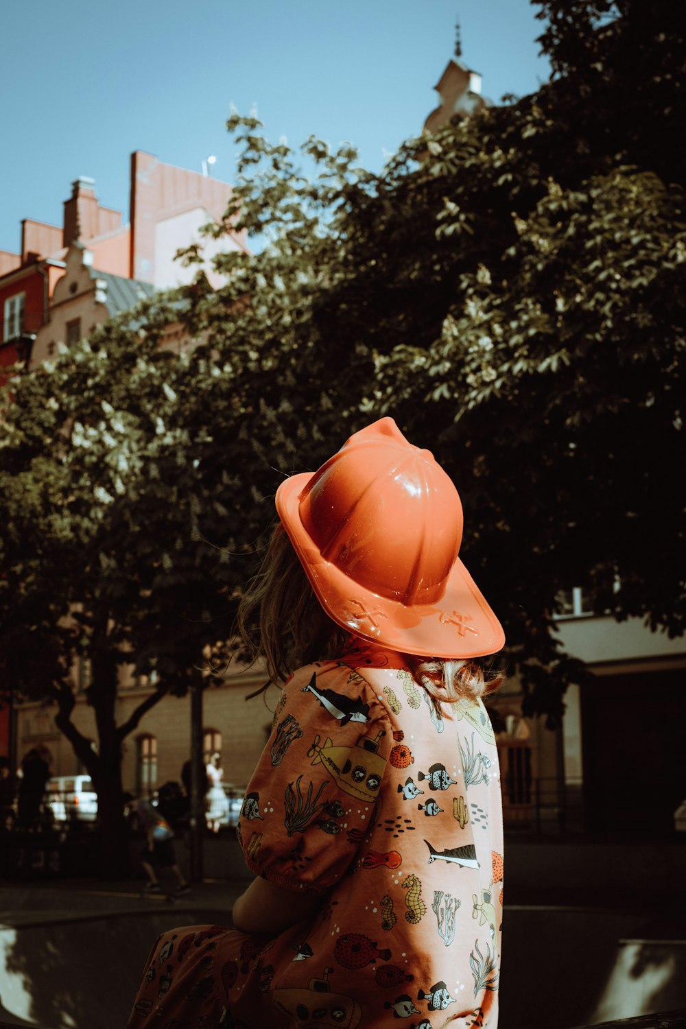 a little girl in a dress and orange hat