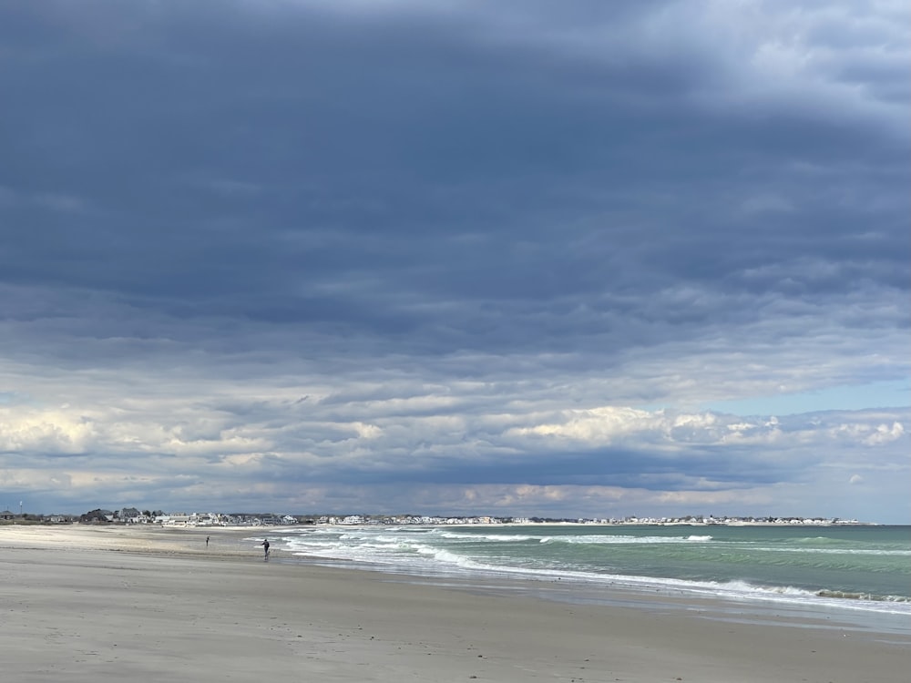 a person is walking on the beach with a surfboard