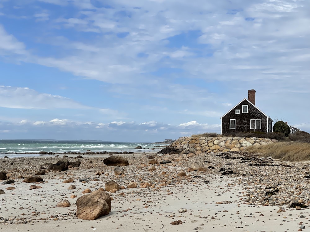 a house sitting on top of a sandy beach next to the ocean