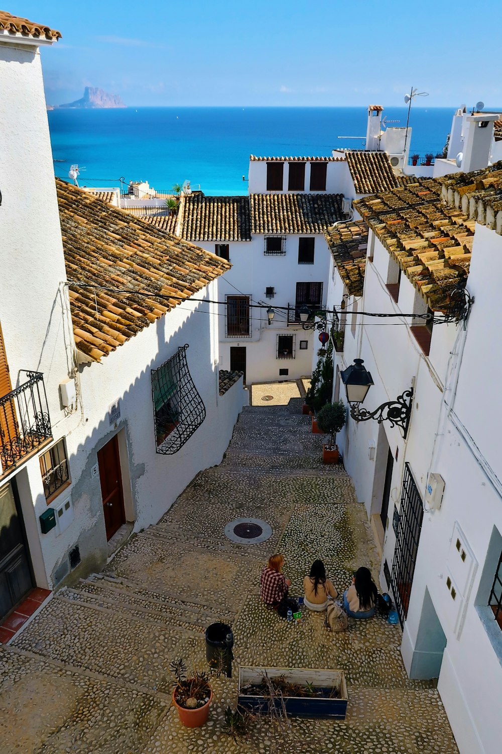 a group of people sitting on top of a cobblestone street