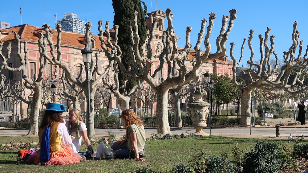 a group of people sitting on top of a lush green field