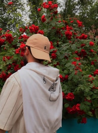 a man in a hat is looking at red flowers