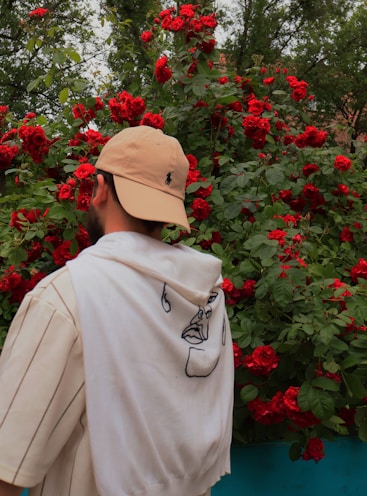 a man in a hat is looking at red flowers