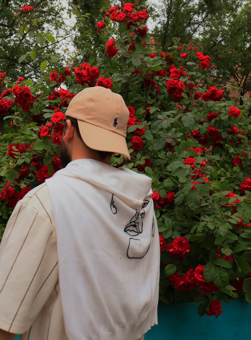a man in a hat is looking at red flowers