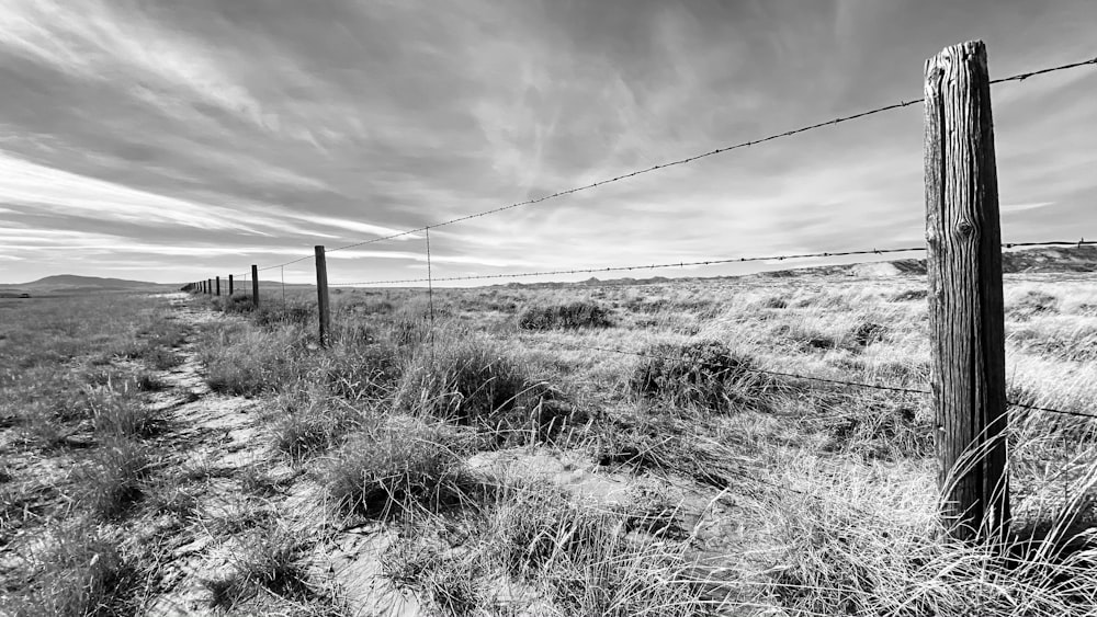 a black and white photo of a fence in the desert