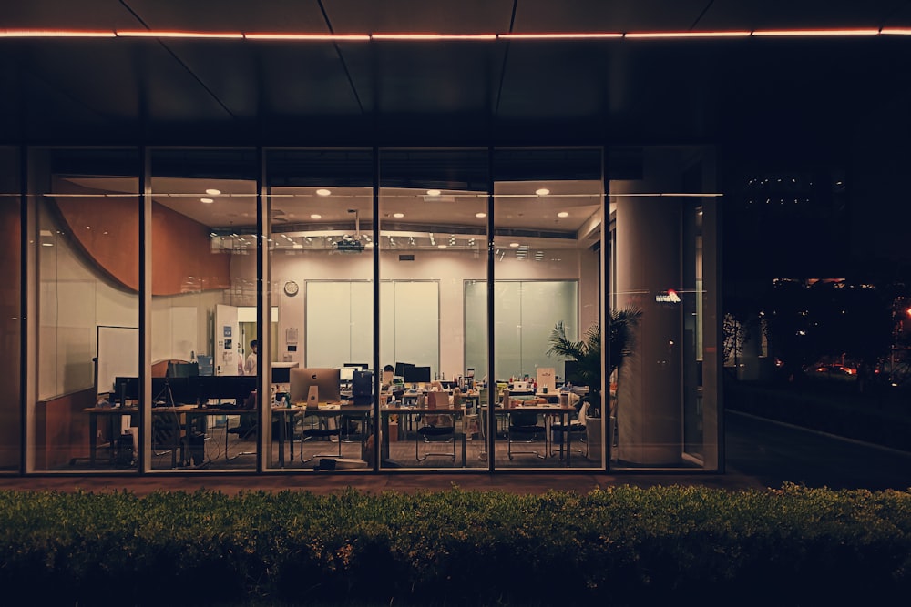 a glass walled office building at night with a view of the city