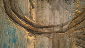 Close-up of tire tracks from heavy equipment on a dusty construction field under a clear sky