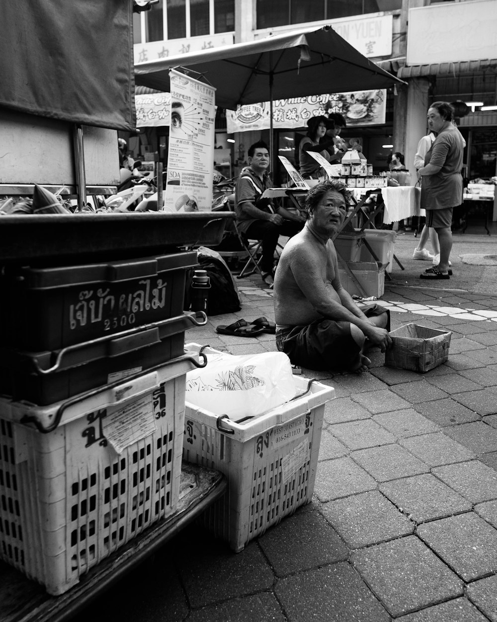 a man sitting on the ground in front of a market