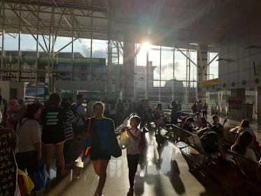 A bustling airport terminal filled with travelers and departure screens.