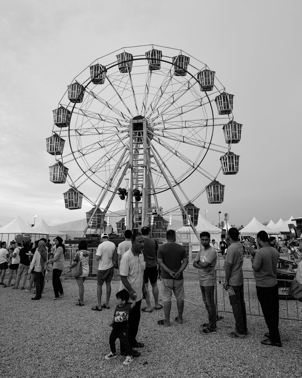 a group of people standing around a ferris wheel