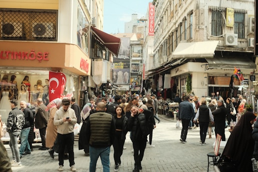 a crowd of people walking down a street next to tall buildings